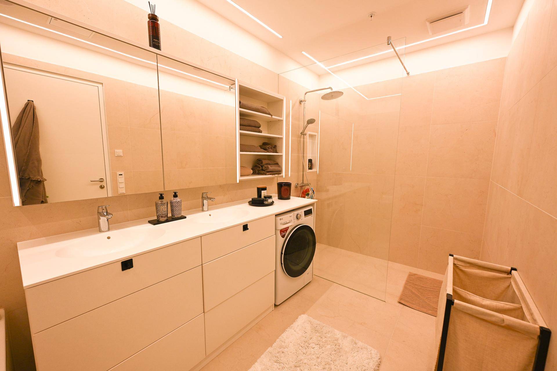 Modernes Badezimmer mit großer Dusche, Doppelwaschbecken und Waschmaschine.