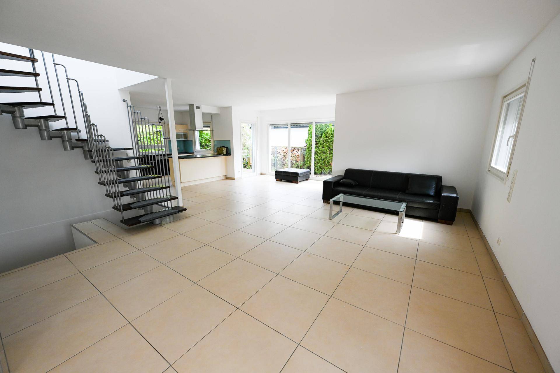 Heller Wohnbereich mit Fliesenboden, bequemer Couch und Zugang zur Terrasse.