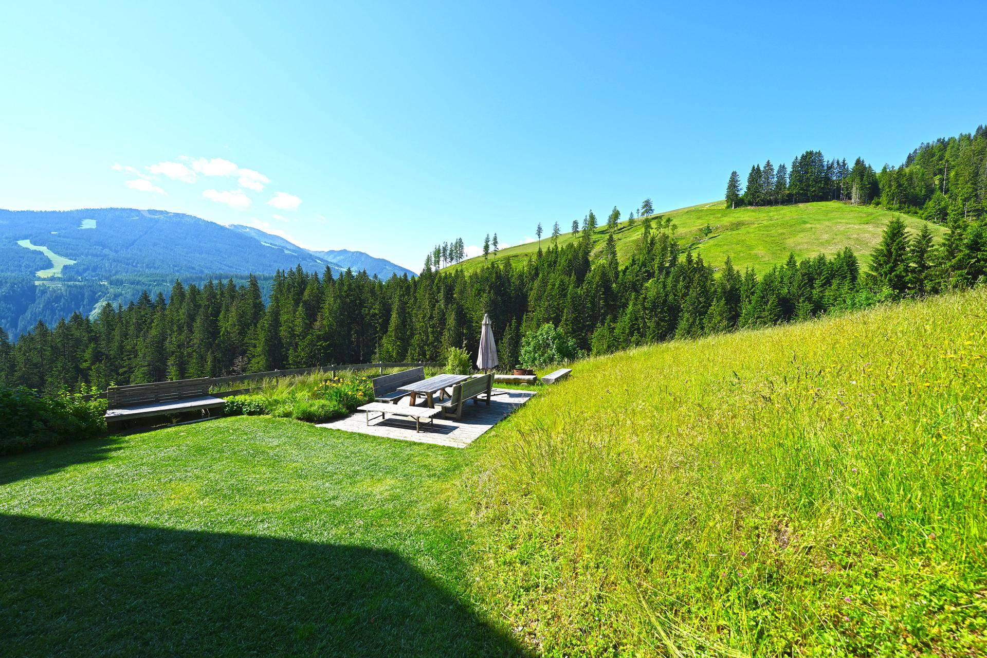Weitläufiger Gartenbereich mit Holzterrasse und Sitzgelegenheiten, ideal für Entspannung im Freien.