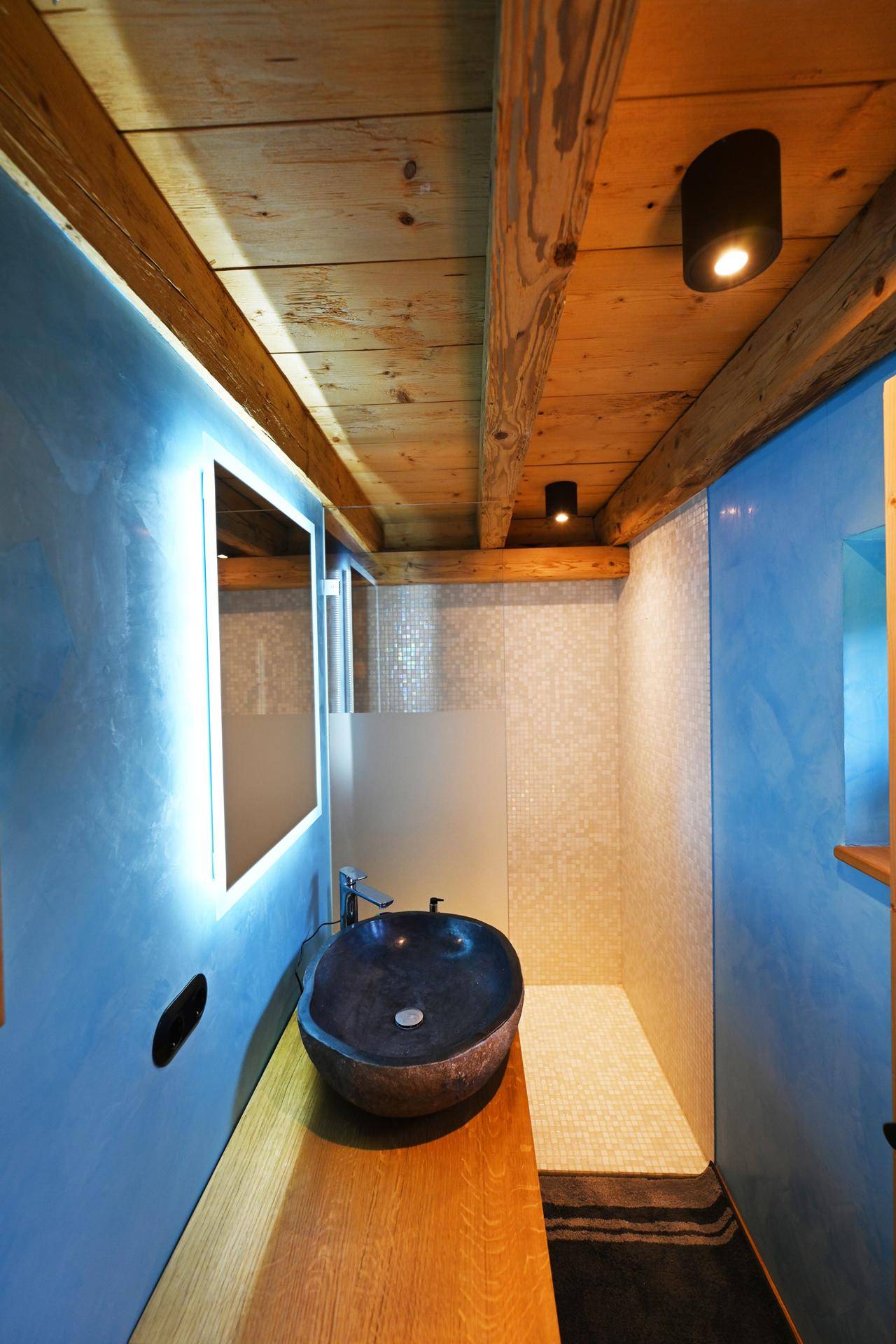 Modernes Badezimmer mit blauen Wänden, Holzdecke und stilvollem Aufsatzwaschbecken.