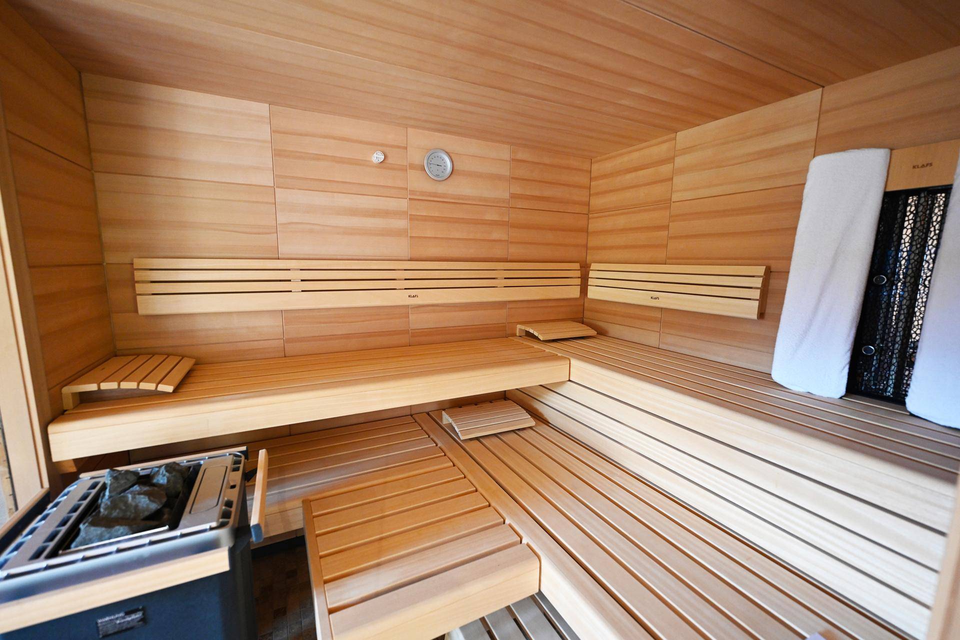 Moderne Holzsauna mit bequemen Bänken und Heizofen, bereit für entspannende Momente.