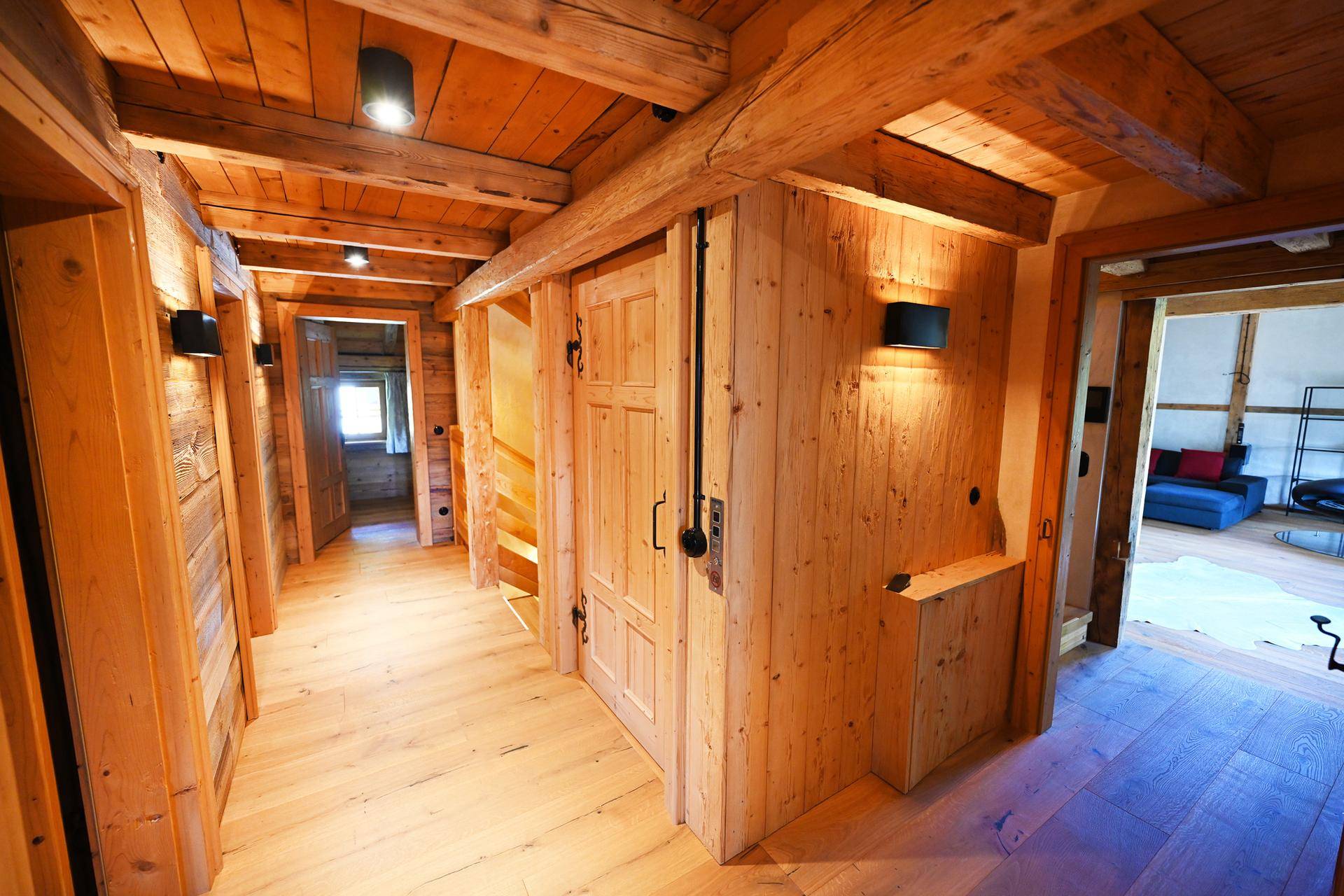 Langer Flur mit Holzwänden, Holzbalkendecke und mehreren Türen im Landhausstil.