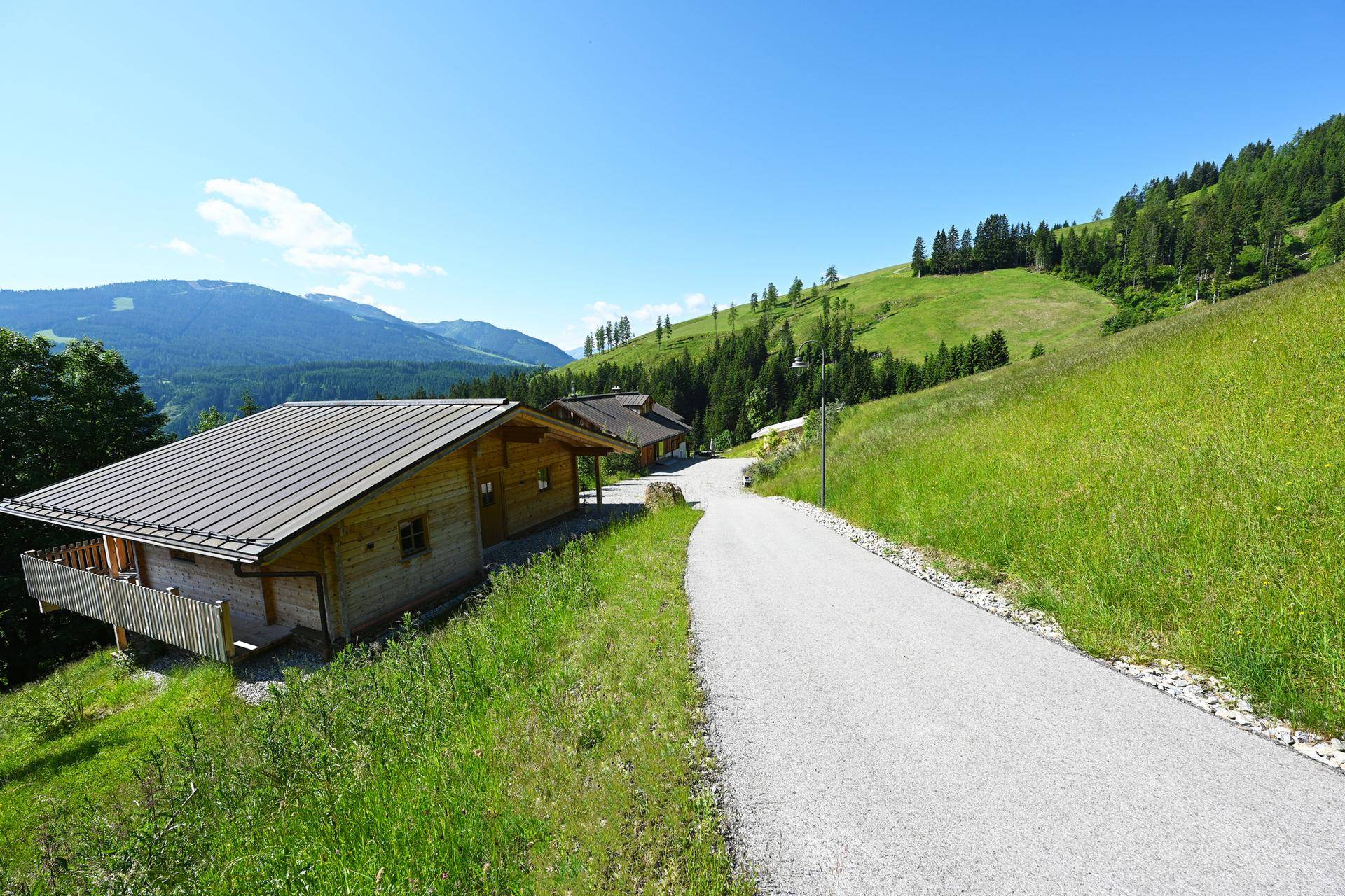 Idyllische Chalet-Anlage mit gepflegtem Weg und atemberaubendem Blick auf die Berglandschaft.