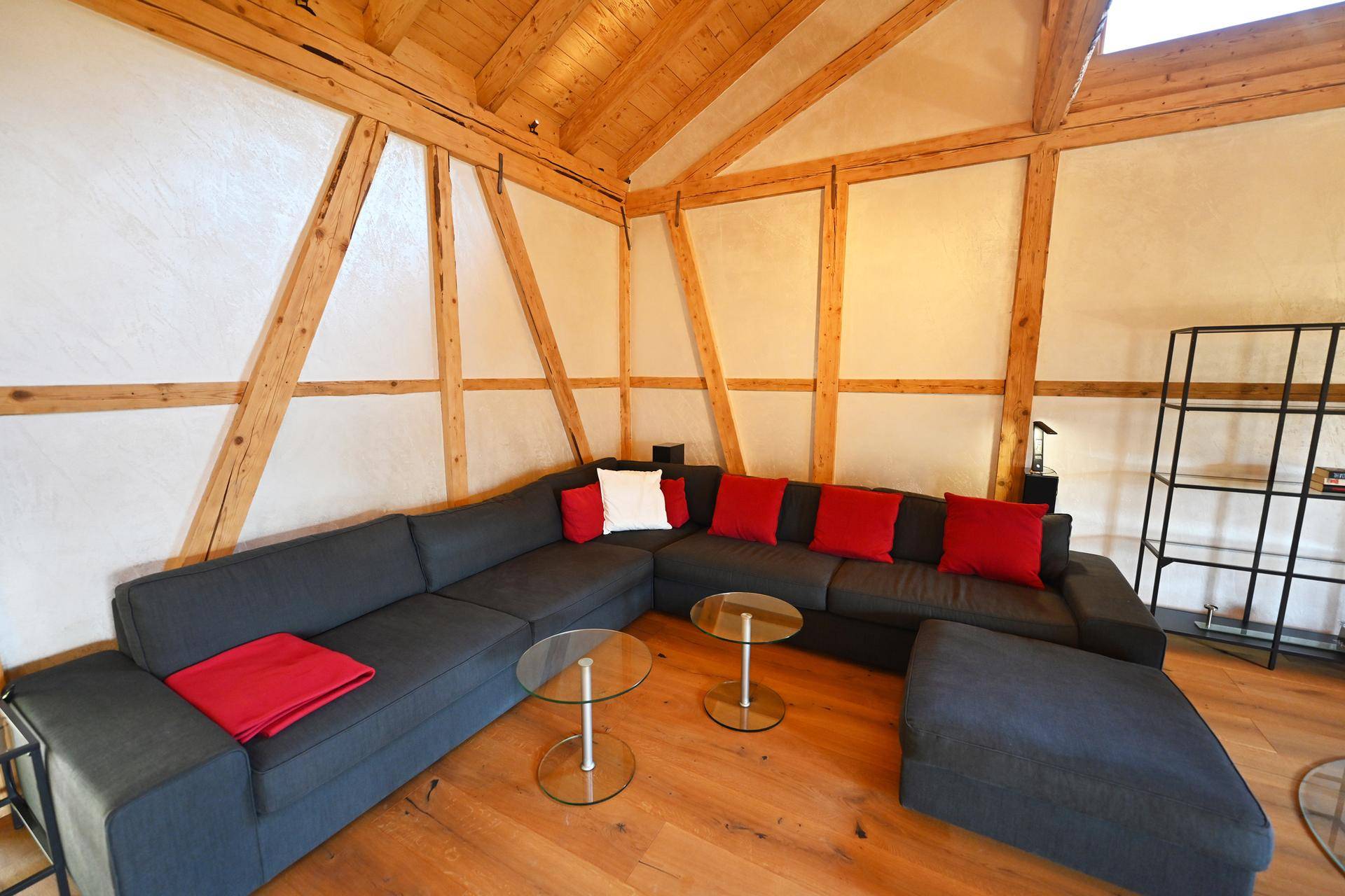 Gemütlicher Wohnbereich mit großem Ecksofa, Glastischen und Holzbalken, ideal zum Entspannen.