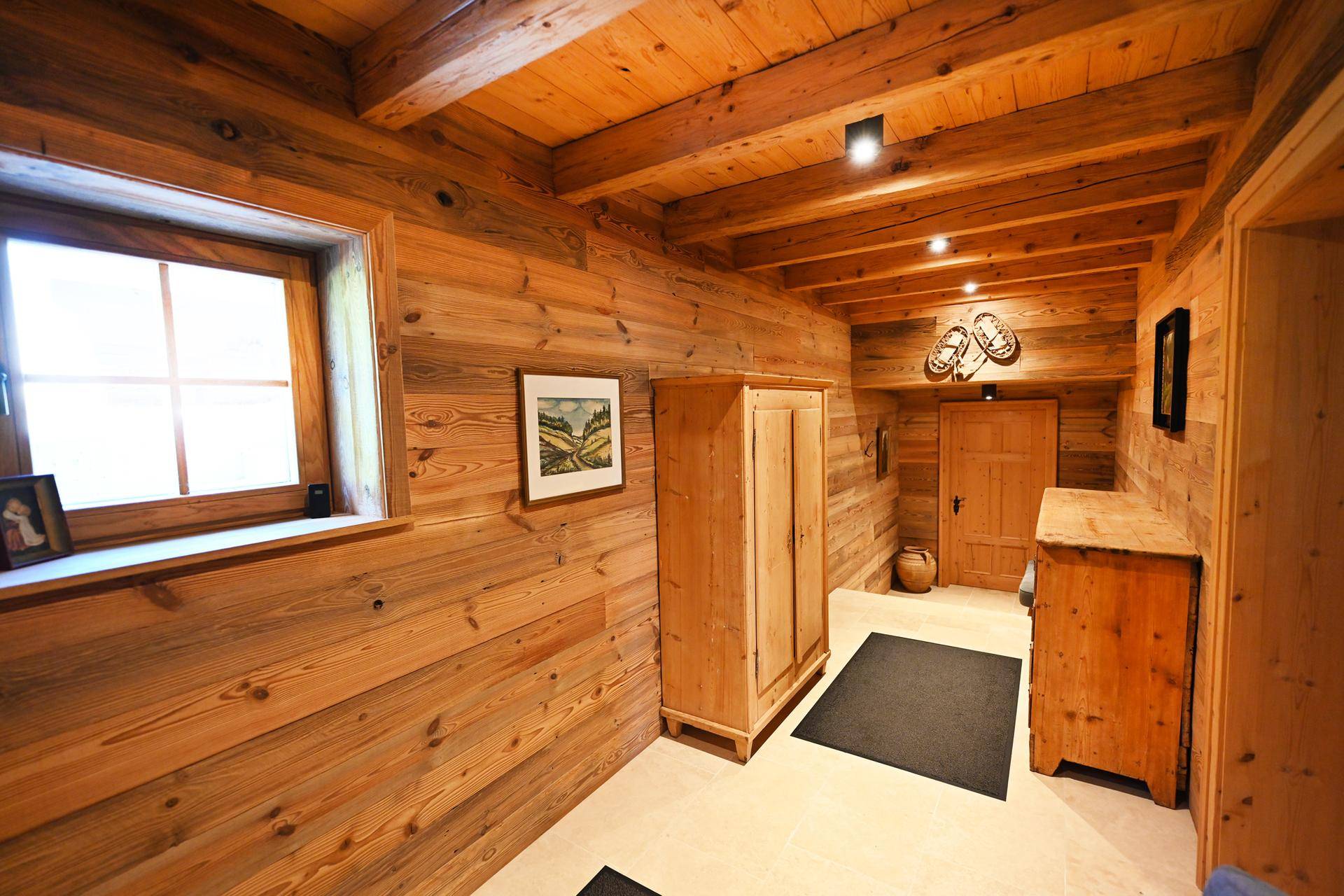 Warmer Eingangsbereich mit Holzwänden und -decken, ausgestattet mit einem Schrank und Kommode.