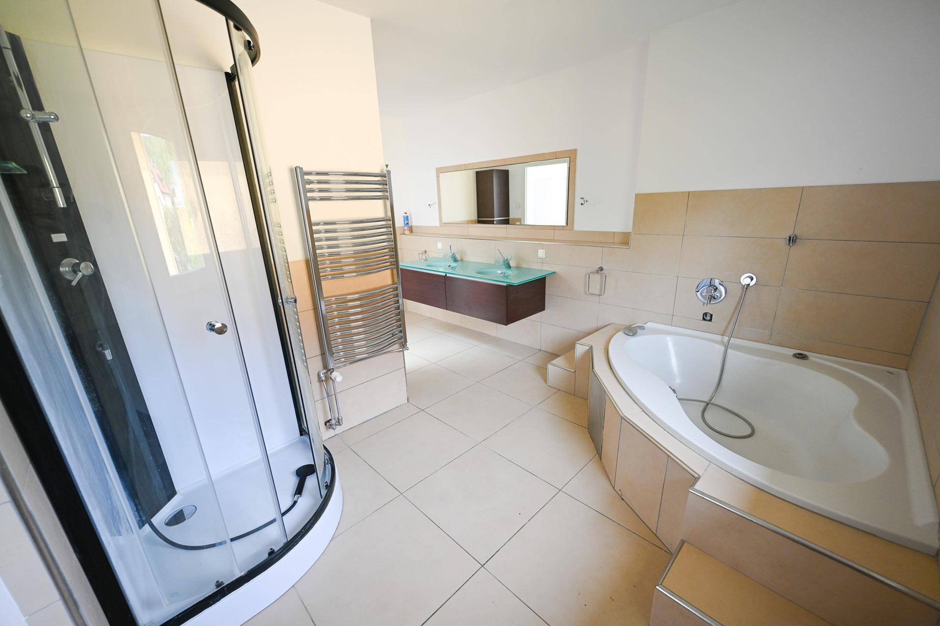 Badezimmer mit Eckbadewanne, Duschkabine und beheiztem Handtuchhalter.
