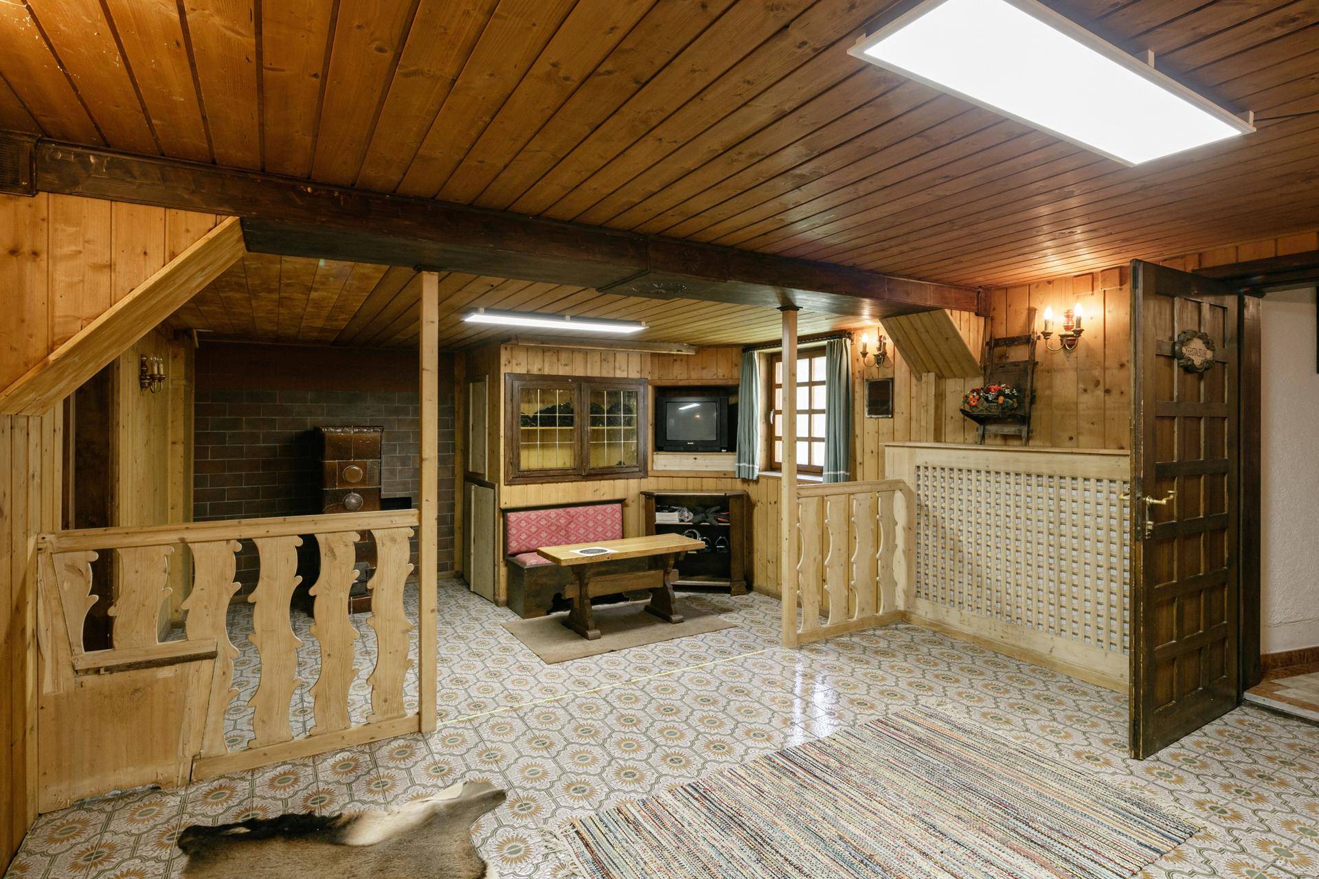 Rustikaler Wohnbereich mit Holzvertäfelung, gemustertem Fliesenboden und traditionellen Möbeln.