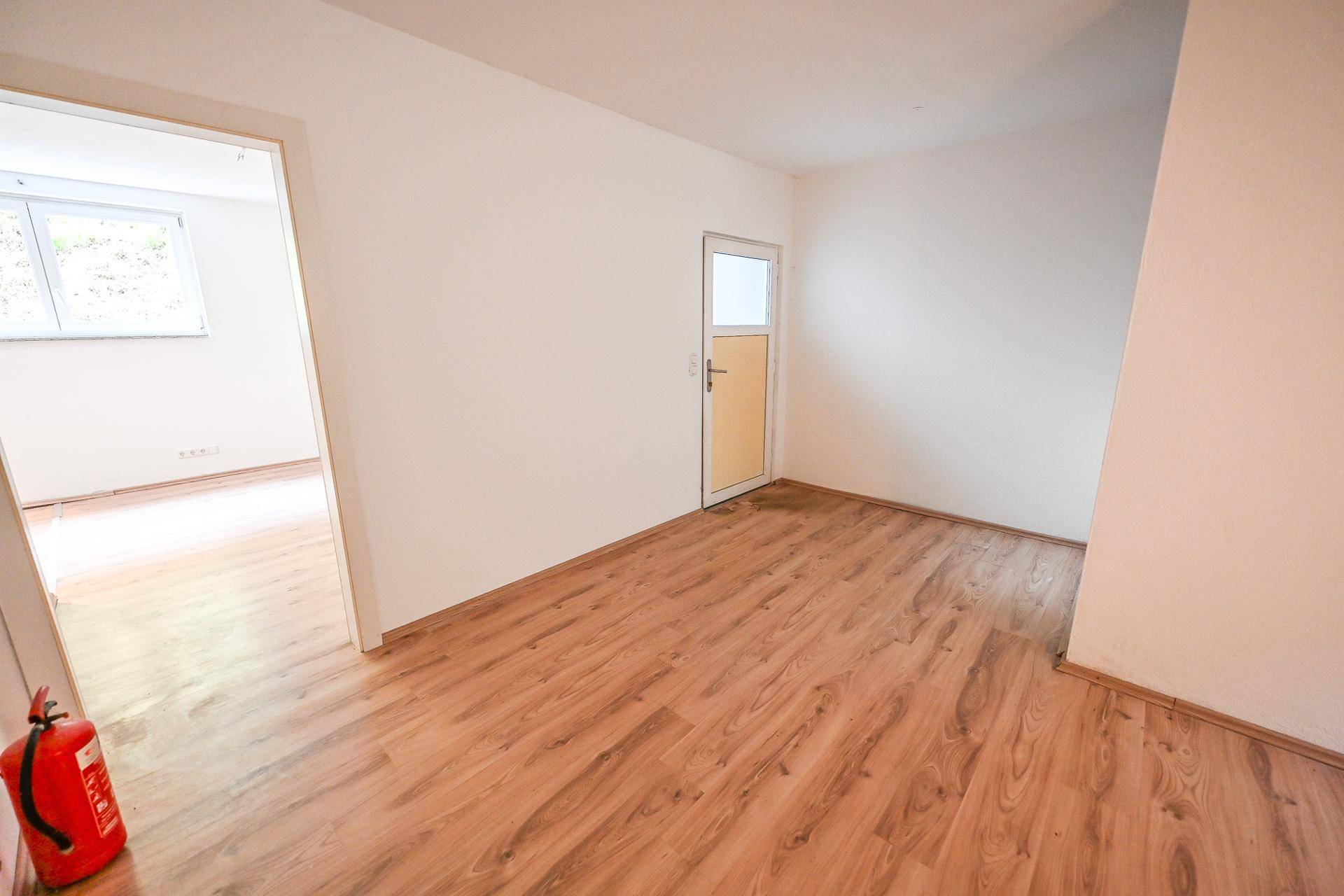 Helles Zimmer mit Laminatboden und Zugang zu weiteren Räumen.