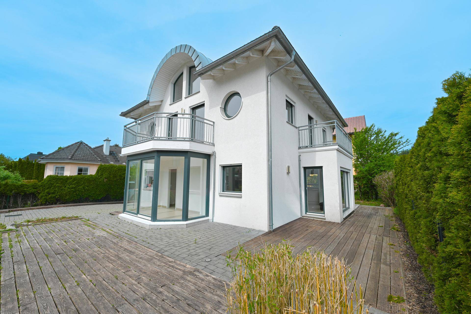 Seitliche Ansicht des Hauses mit großer Holzterrasse und Zugang zum Garten.