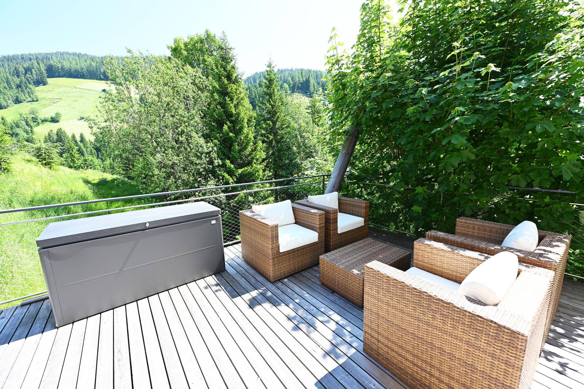 Geräumige Holzterrasse mit gemütlichen Korbmöbeln und weitem Blick ins Grüne.