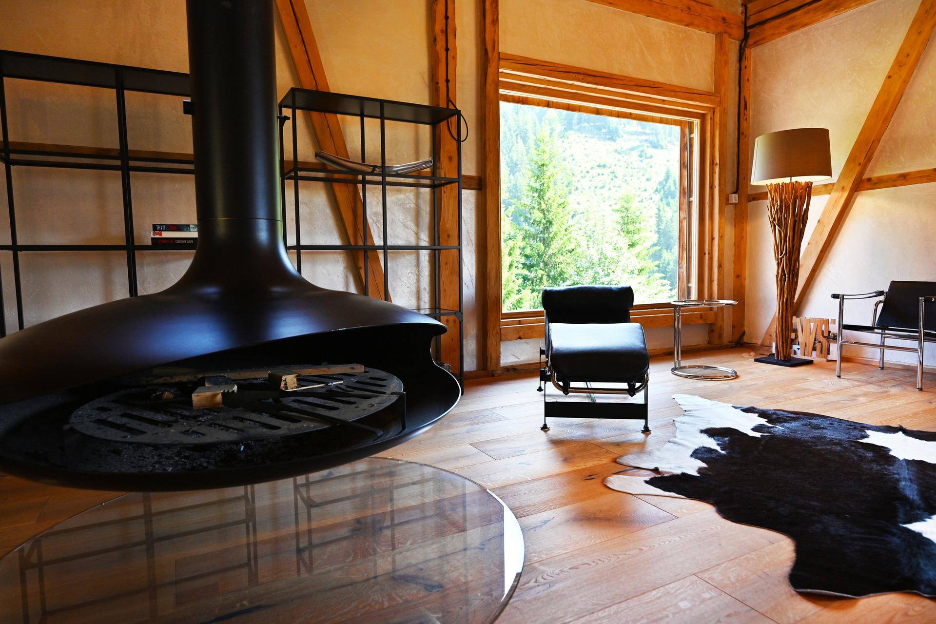 Moderner Kamin im Wohnzimmer mit großen Fenstern und Blick auf die Natur.