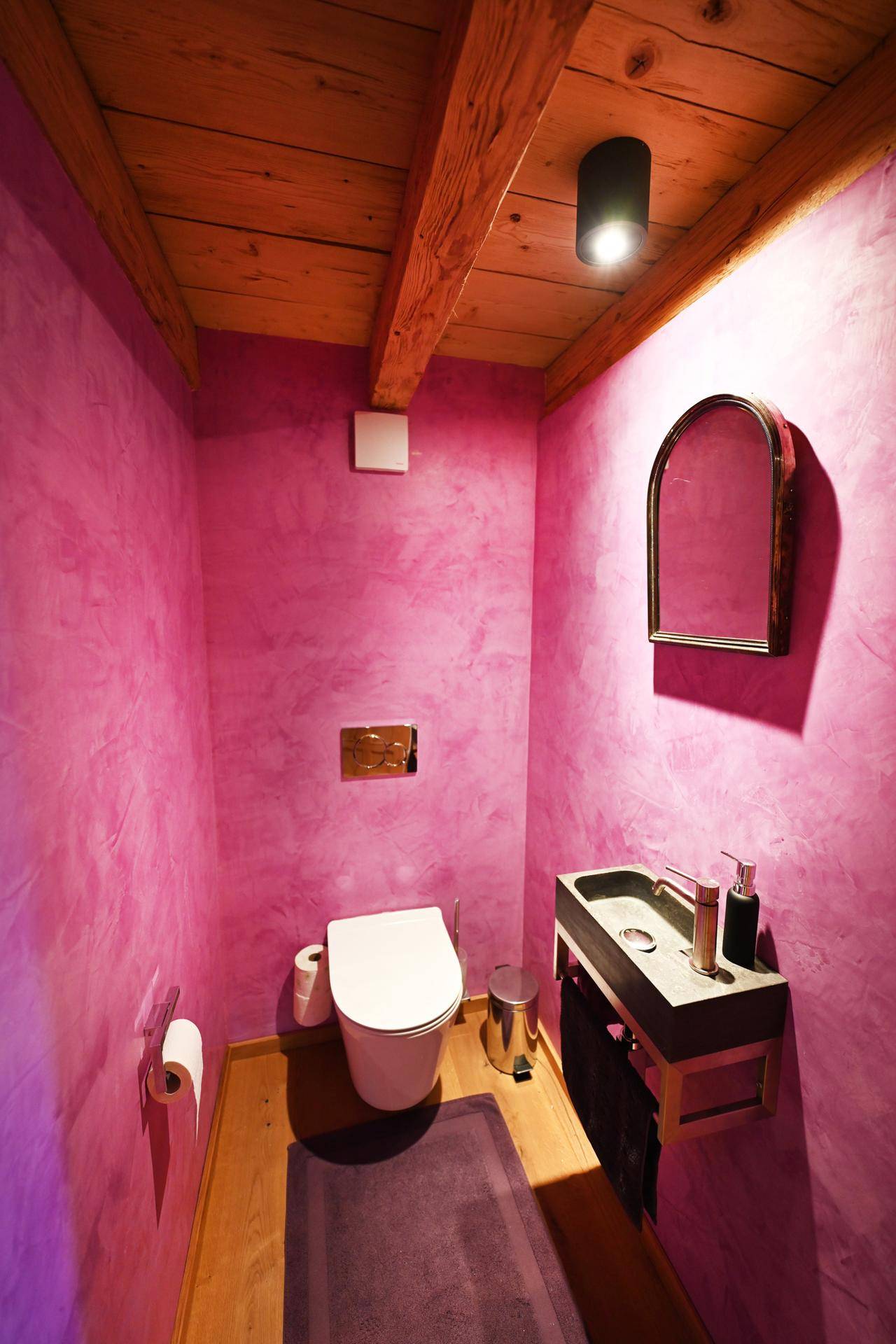 Kleines Gäste-WC mit pinkfarbenen Wänden, Holzdecke und modernem Waschbecken.