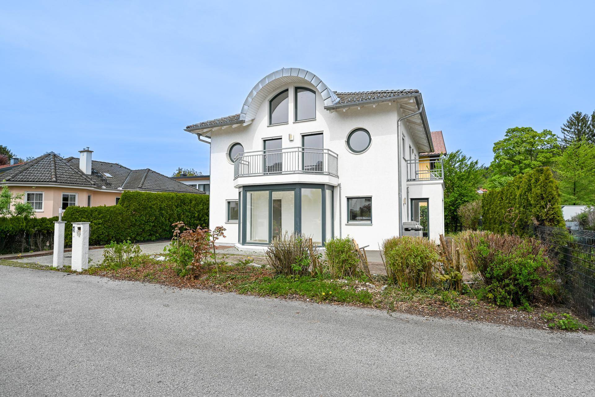 Vorderansicht des modernen Einfamilienhauses mit großen Fenstern und Balkon.