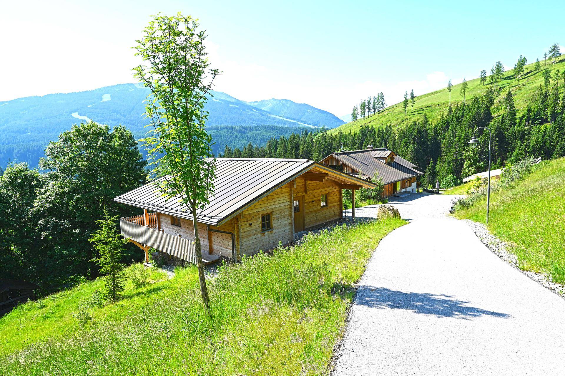 Mehrere charmante Chalets in alpiner Umgebung, verbunden durch einen malerischen Weg.