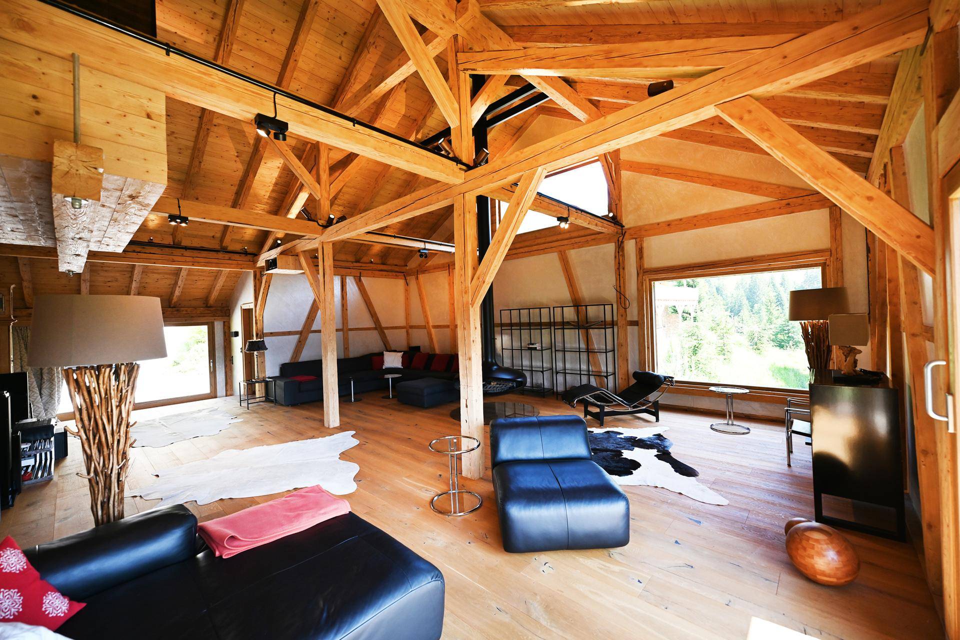 Großzügiges Wohnzimmer mit hohen Holzbalkendecken, großen Fenstern und Bergblick.