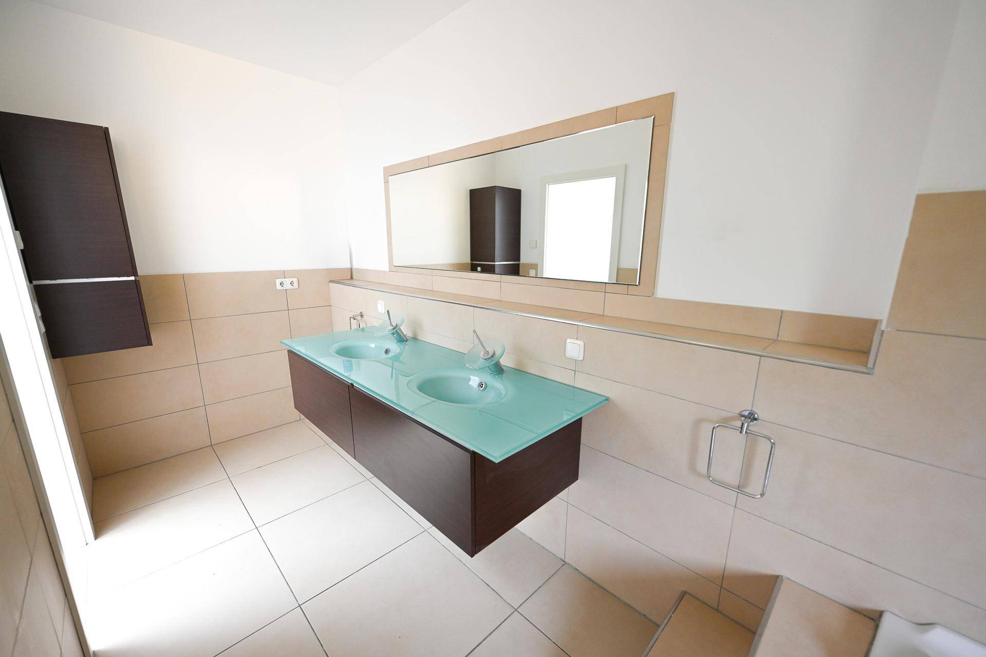 Modernes Badezimmer mit Doppelwaschbecken, großem Spiegel und Fliesen.