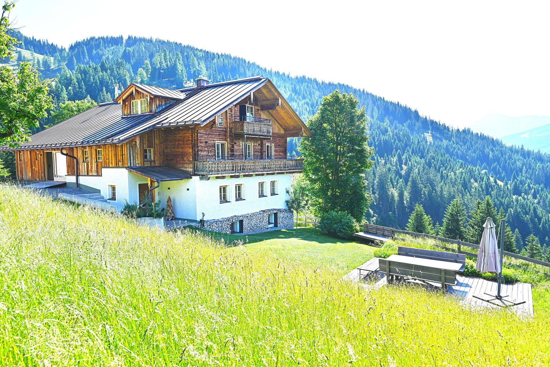 Malerisches Chalet mit Holzbalkonen und einer gemütlichen Terrasse, umgeben von grünen Wiesen und Wäldern.