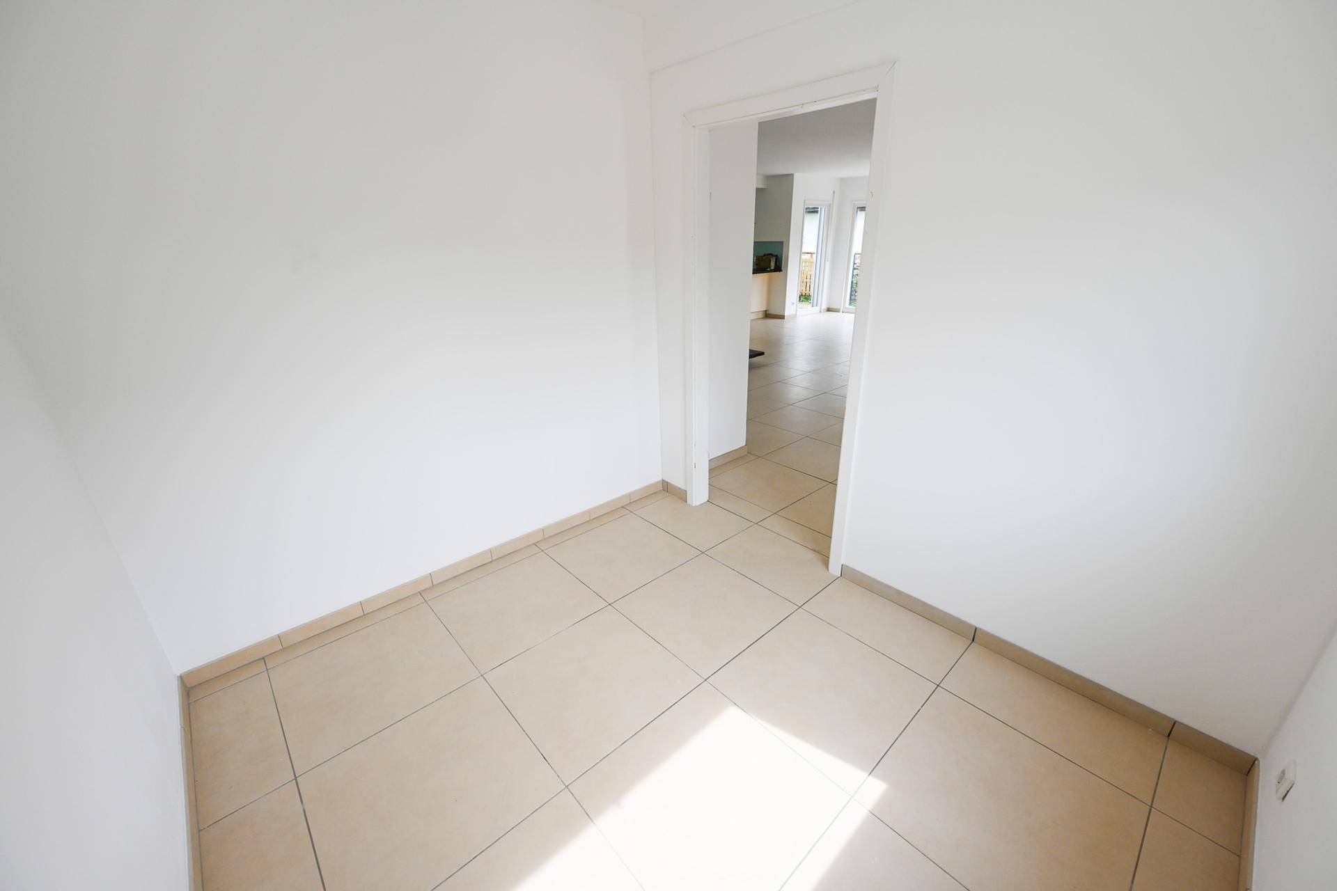 Freundliches Zimmer mit Fliesenboden und Zugang zu weiteren Räumen.