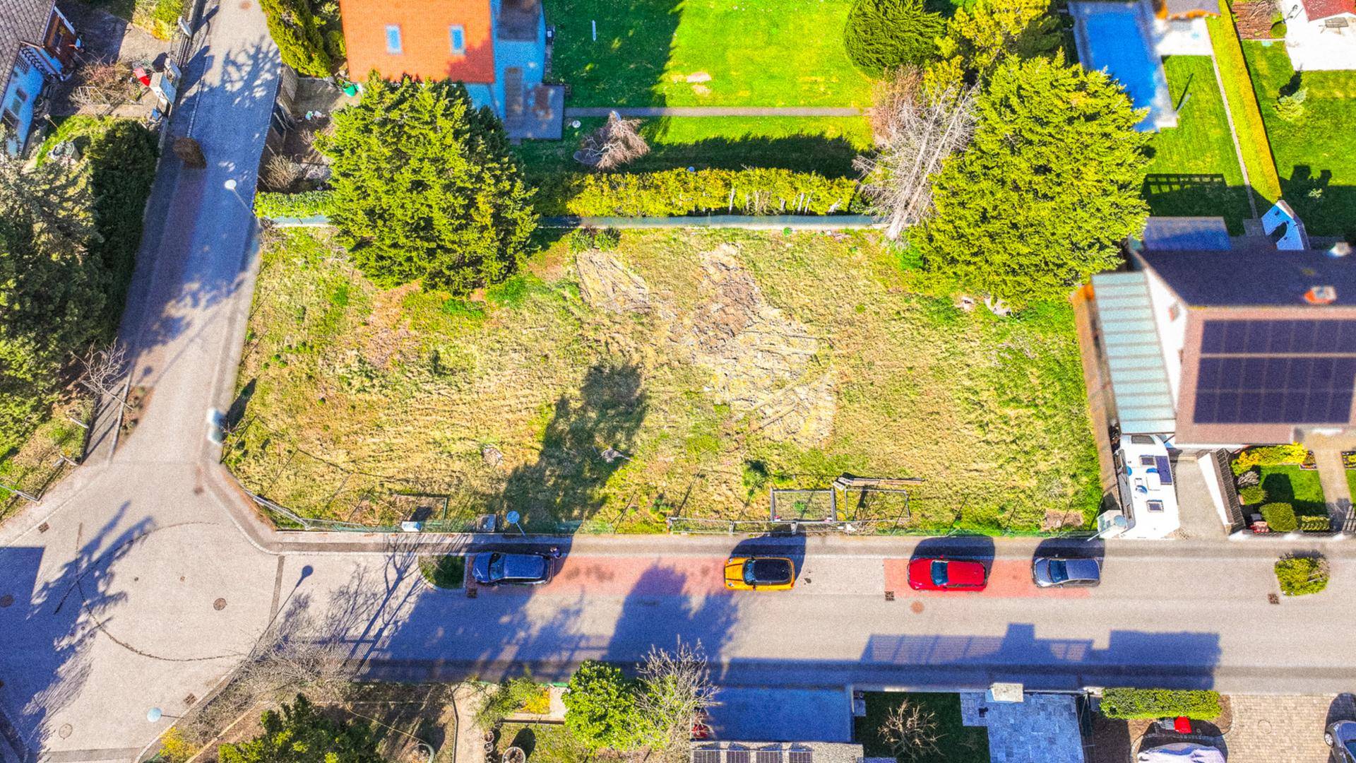Senkrechte Luftaufnahme des unbebauten Grundstücks, umgeben von einer Wohnstraße und Gärten.
