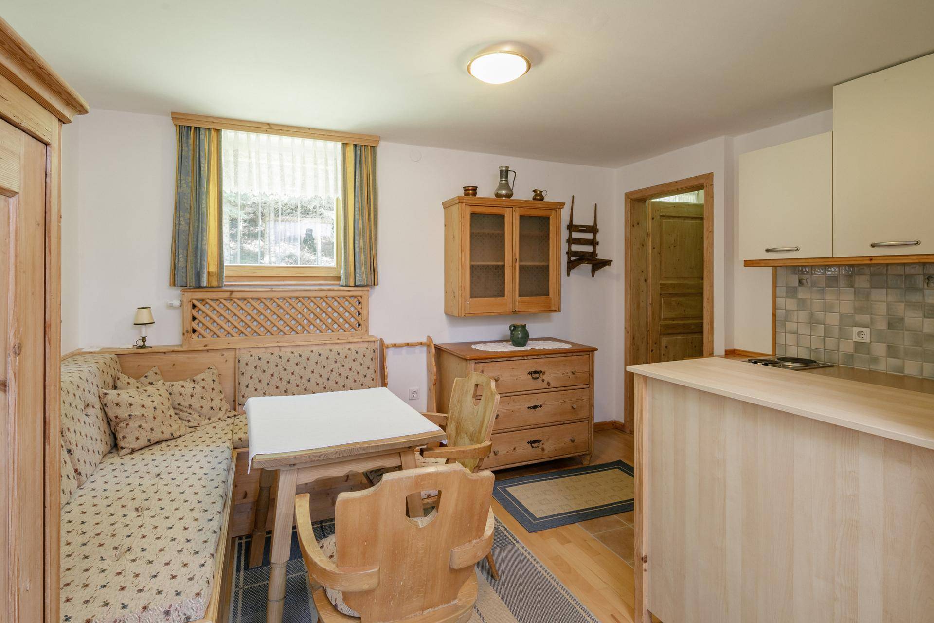Rustikaler Wohn-Essbereich mit Holzboden, Eckbank und einer kleinen Küchenzeile im Landhausstil.