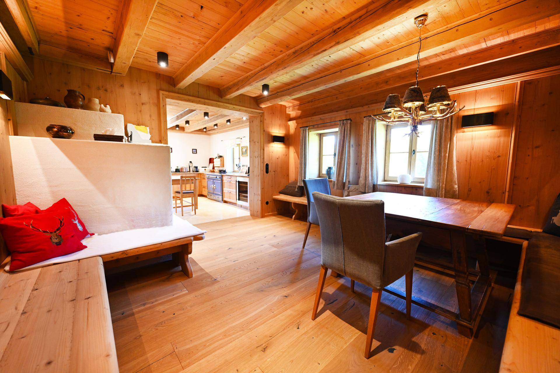 Gemütlicher Essbereich mit Holztisch und Bänken, offen zur Küche, mit traditionellem Kachelofen.