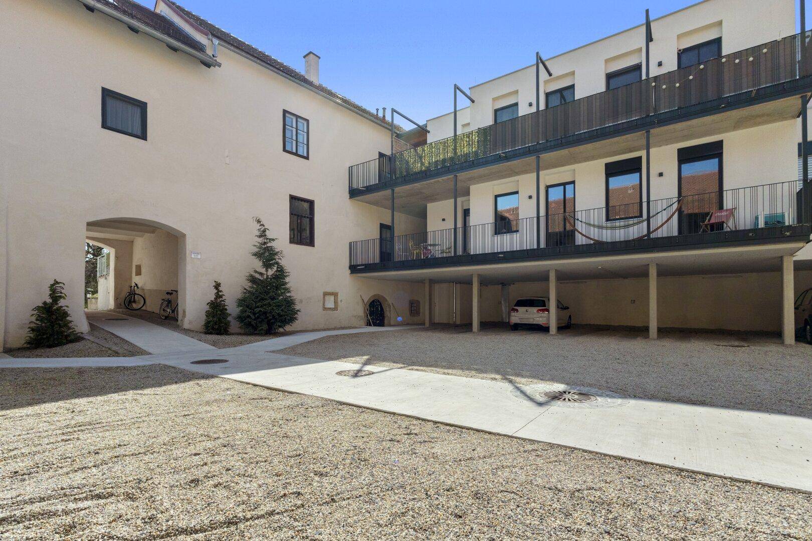 Innenhof eines Wohnkomplexes mit Balkonen, Parkplätzen und historischer Architektur.