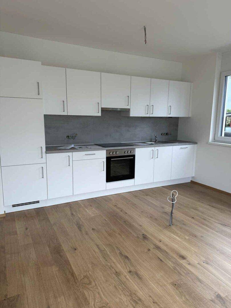 Moderne Einbauküche in Weiß mit integriertem Backofen und viel Stauraum.