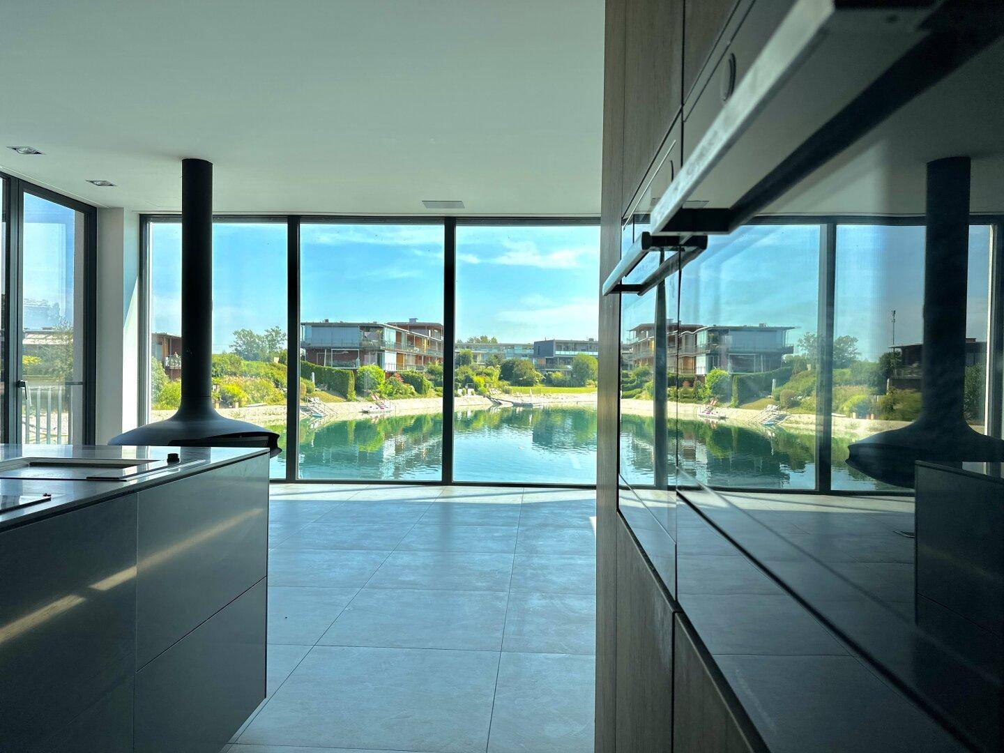 Moderne Küche mit integrierten Geräten und weitem Blick auf den See.