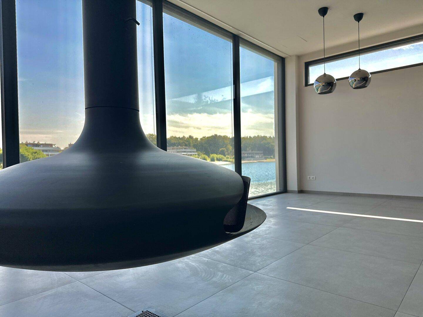 Heller Wohnbereich mit modernem Hängekamin und weitem Blick auf den See.