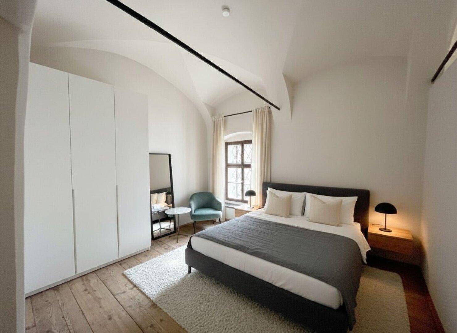 Modernes Schlafzimmer mit gewölbter Decke, Holzboden und großem Kleiderschrank.