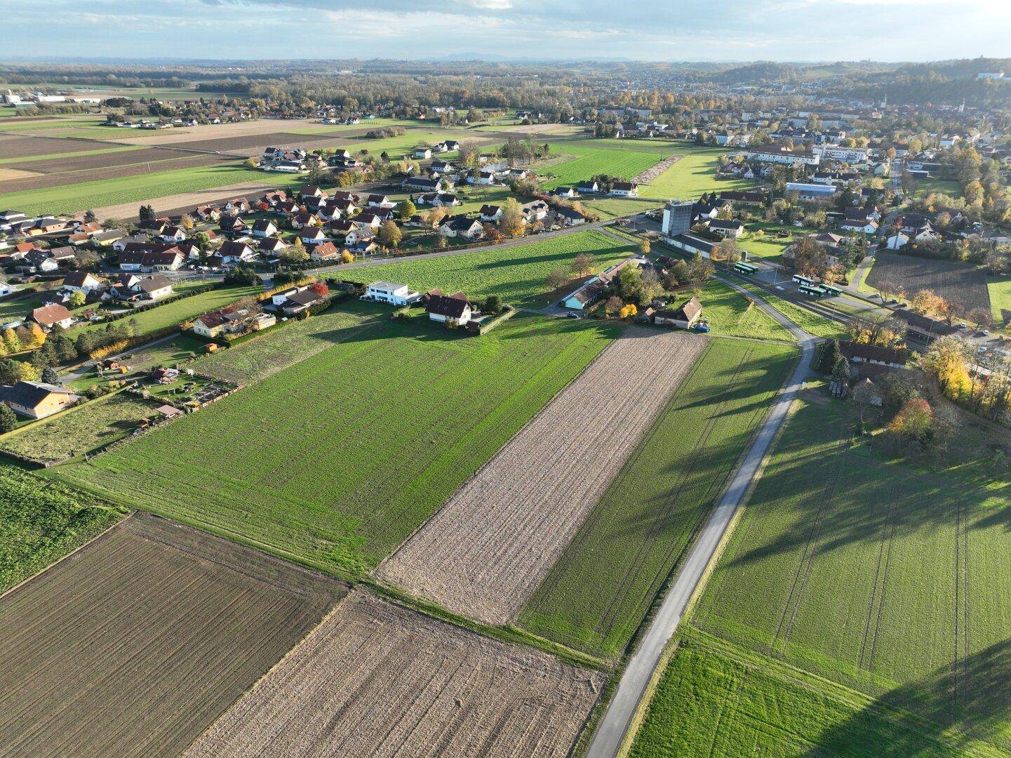 Luftaufnahme einer ländlichen Siedlung umgeben von Feldern und grüner Landschaft.