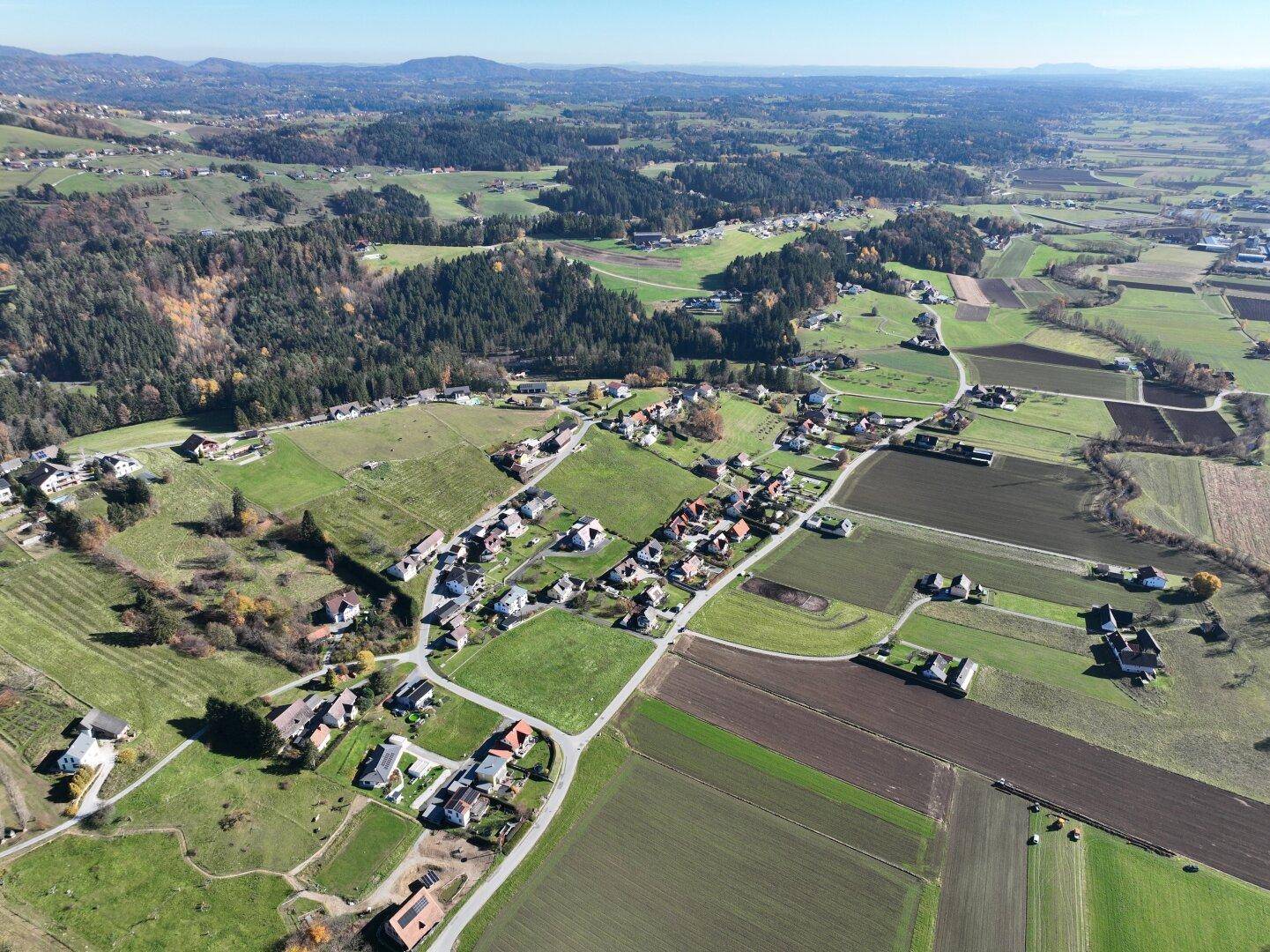 Panoramablick aus der Vogelperspektive auf eine ausgedehnte ländliche Landschaft mit Wäldern und Siedlungen.