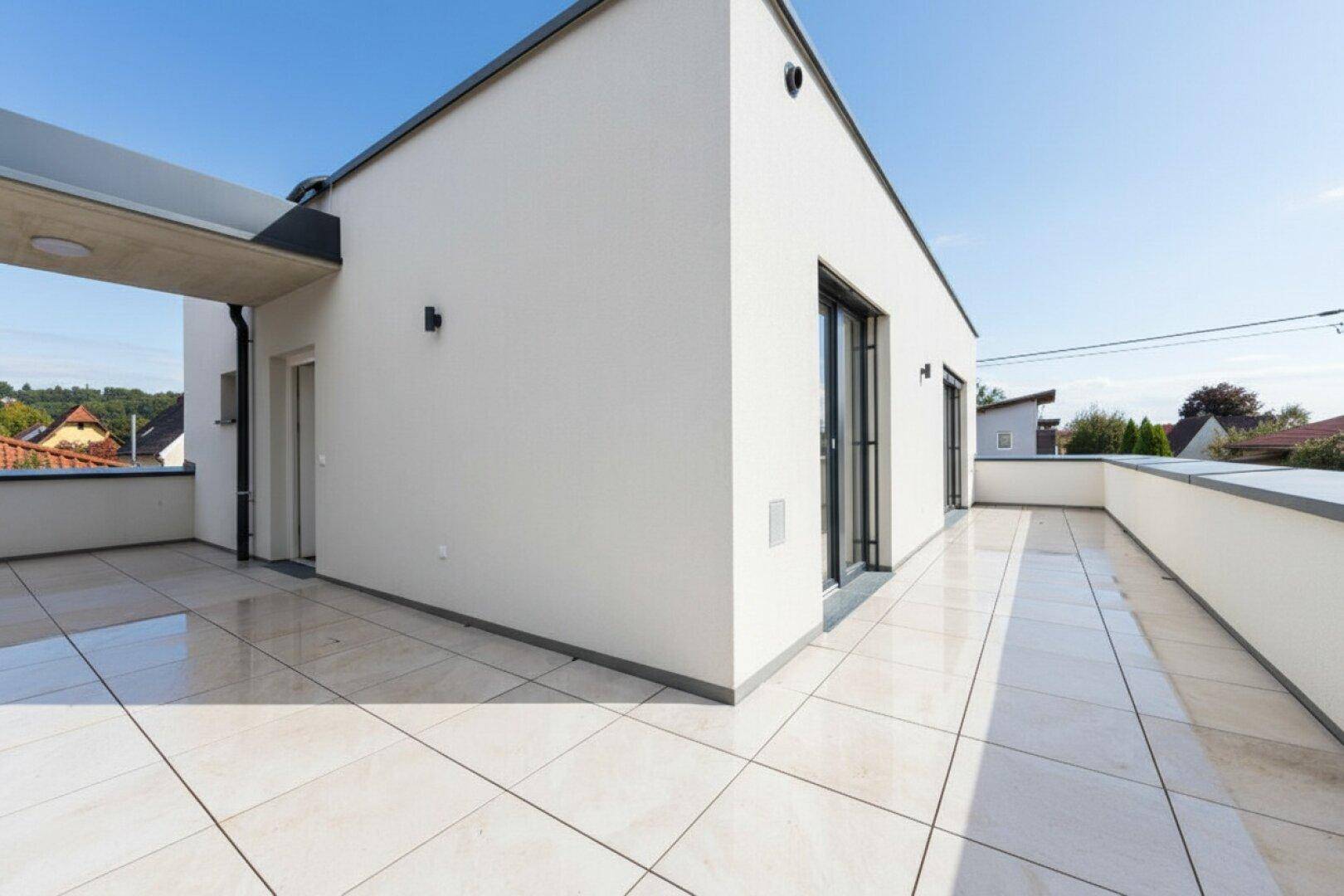 Große, geflieste Terrasse mit moderner Architektur und weitem Blick in die Umgebung.