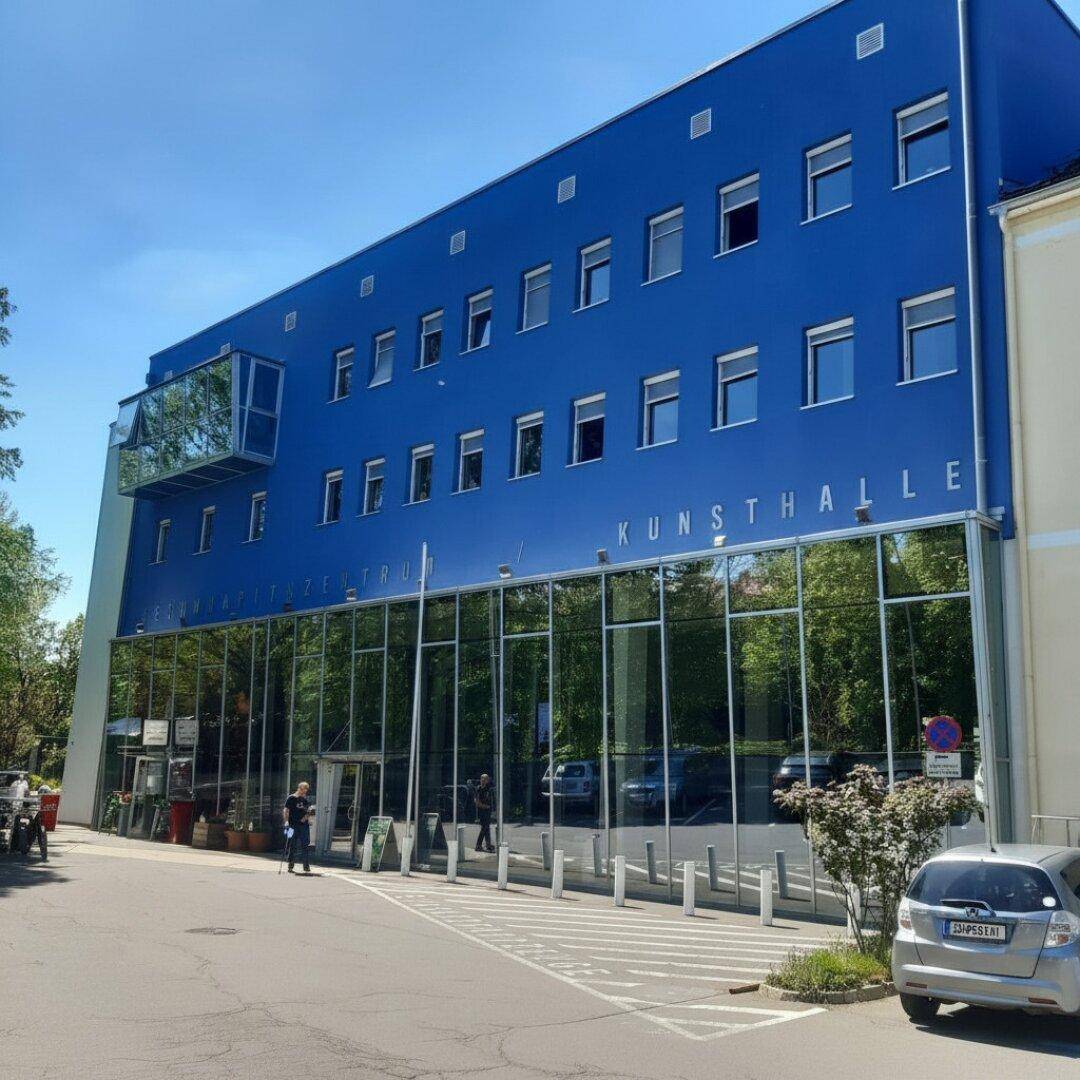 Modernes Gebäude mit blauer Fassade und großer Glasfront, beherbergt eine Kunsthalle.