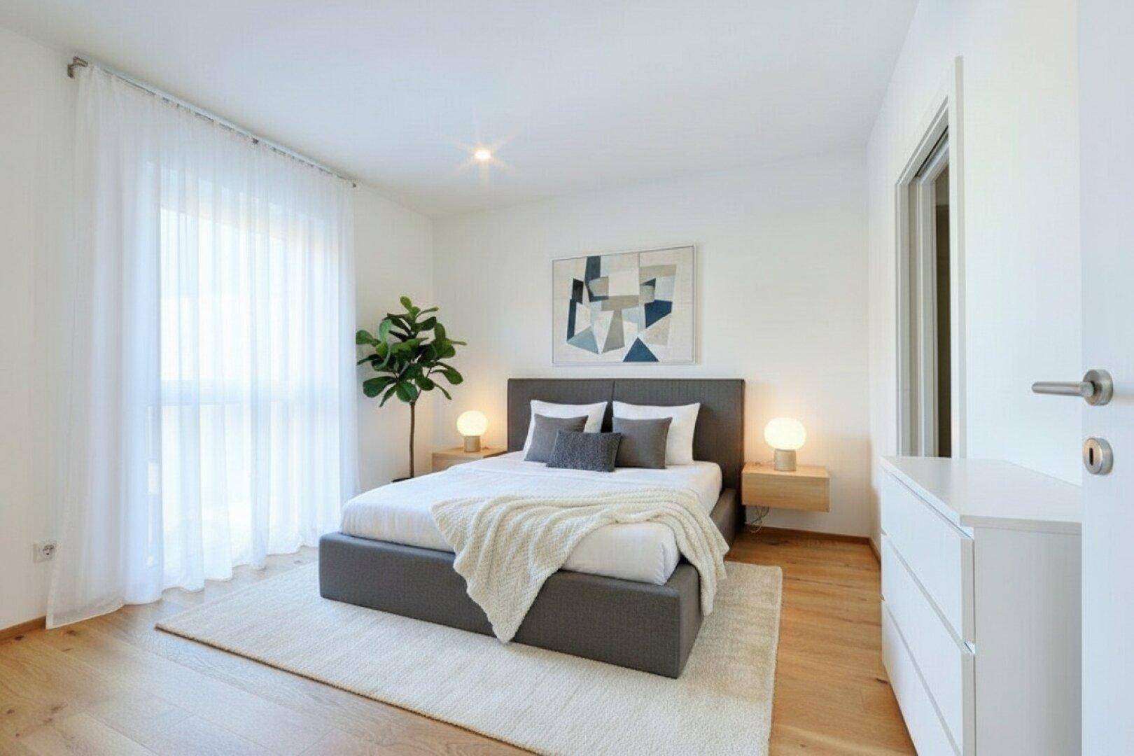 Modern eingerichtetes Schlafzimmer mit Doppelbett, Holzboden und großen Fenstern mit Vorhängen.