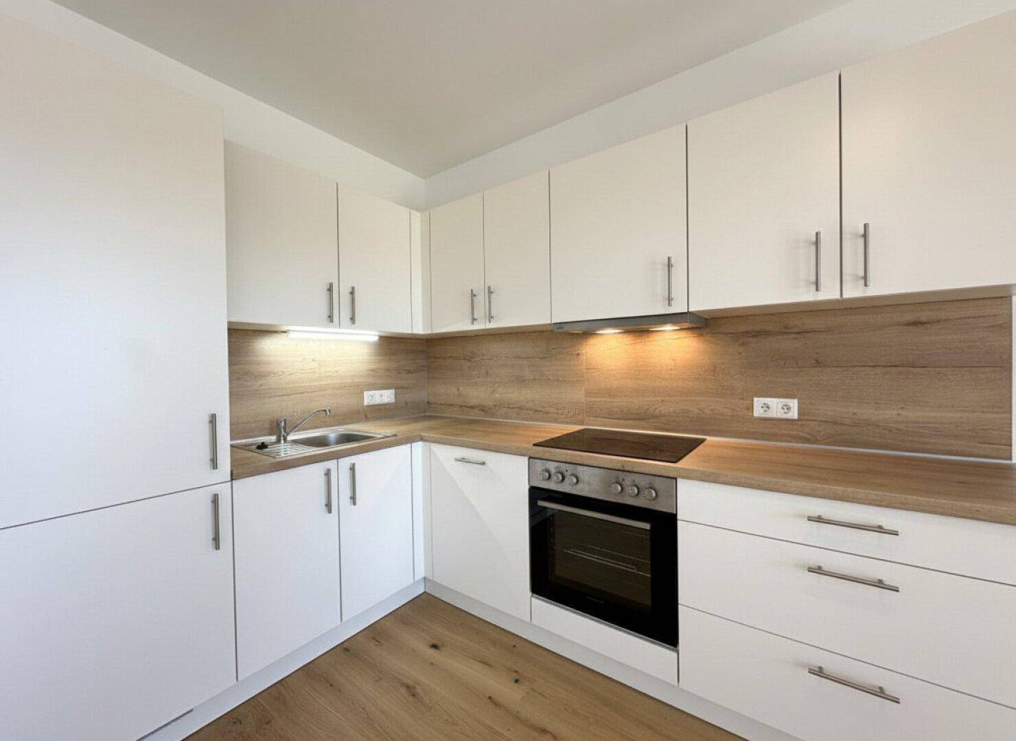 Moderne Einbauküche mit weißen Schränken, Holz-Arbeitsplatten und integrierten Geräten.