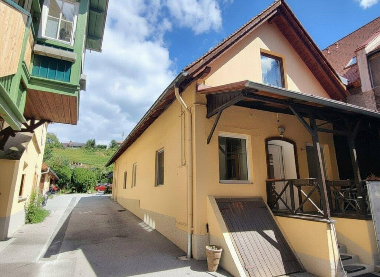 Charmantes Haus mit überdachter Terrasse und Blick auf die umliegende Landschaft und Weinberge.