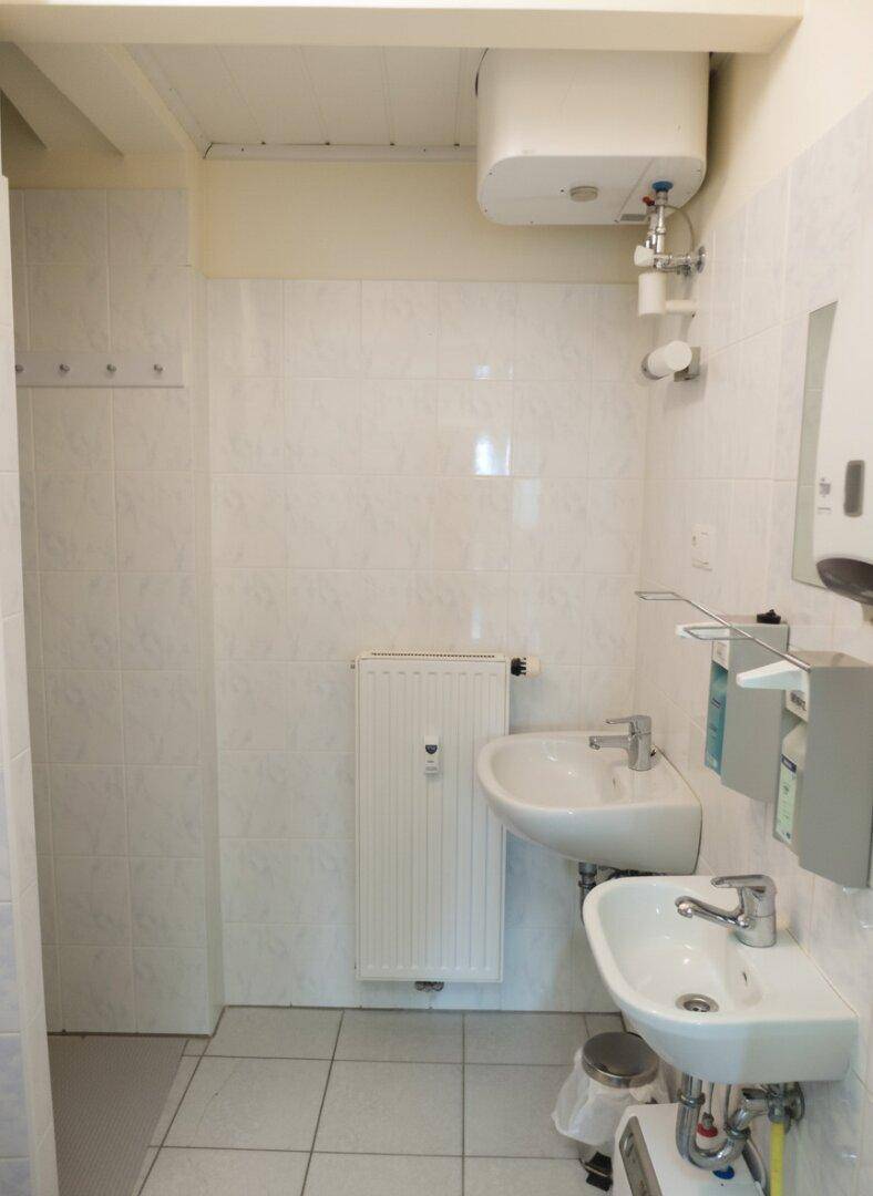 Gefliestes Badezimmer mit zwei Waschbecken und Heizkörper an der Wand.