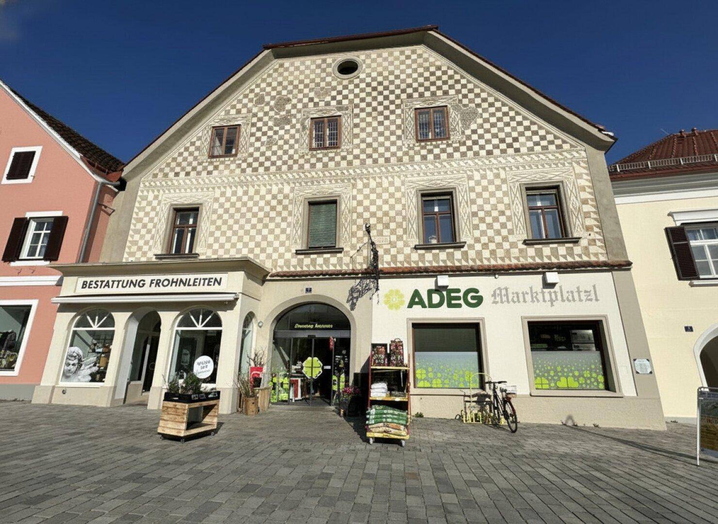 Detailansicht der historischen Fassade mit Schachbrettmuster und Ladenfronten im Erdgeschoss.