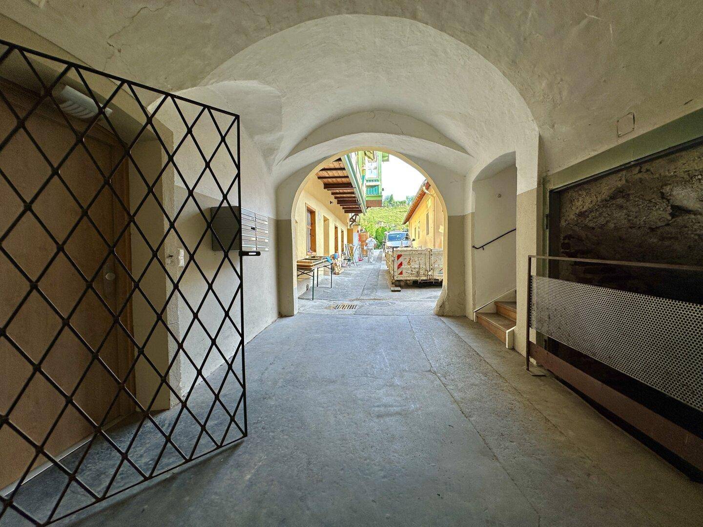 Historischer Torbogen führt durch einen gewölbten Gang zu einem Innenhof oder Hinterhofbereich.
