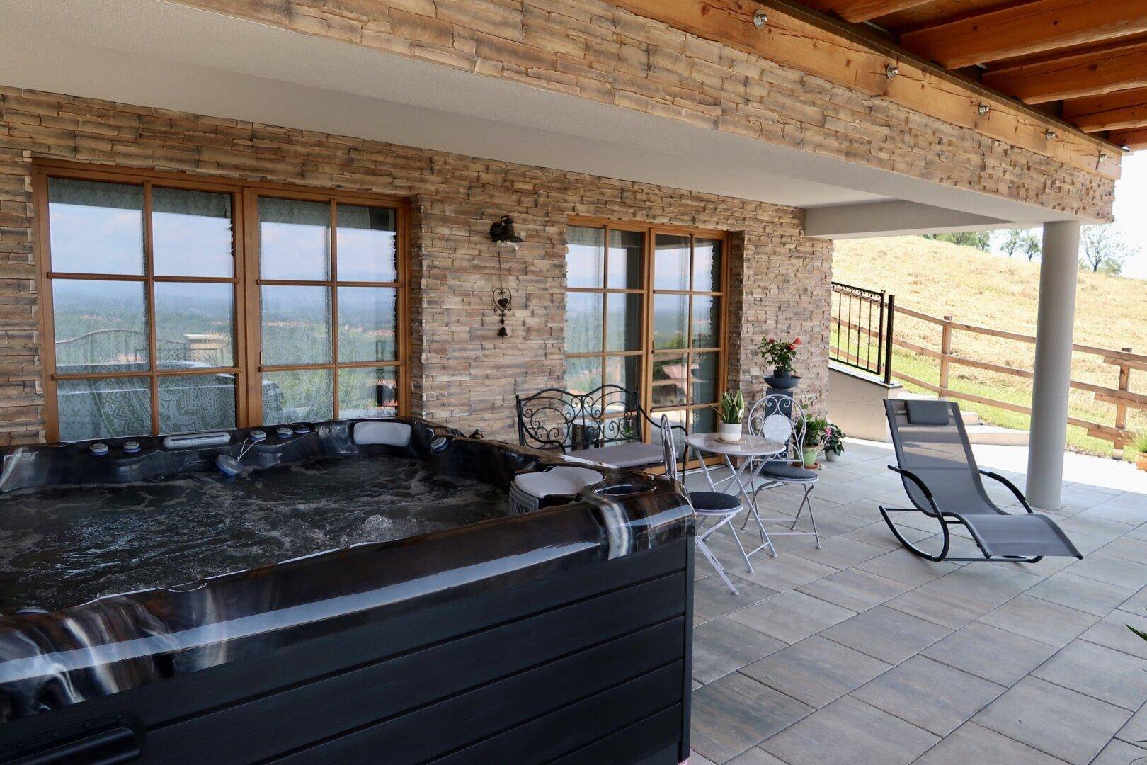 Entspannungsbereich auf der Terrasse mit Whirlpool, Liegestuhl und Blick auf die weite Landschaft.