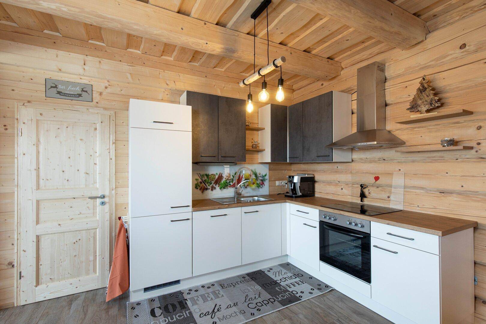 Moderne Einbauküche mit weißen und grauen Schränken in einem gemütlichen Holzhaus.
