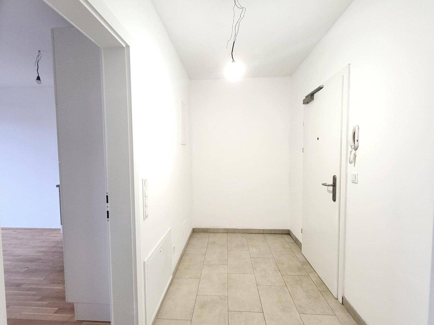 Eingangsbereich mit hellen Fliesen und einer modernen Wohnungstür, schlicht und funktional.