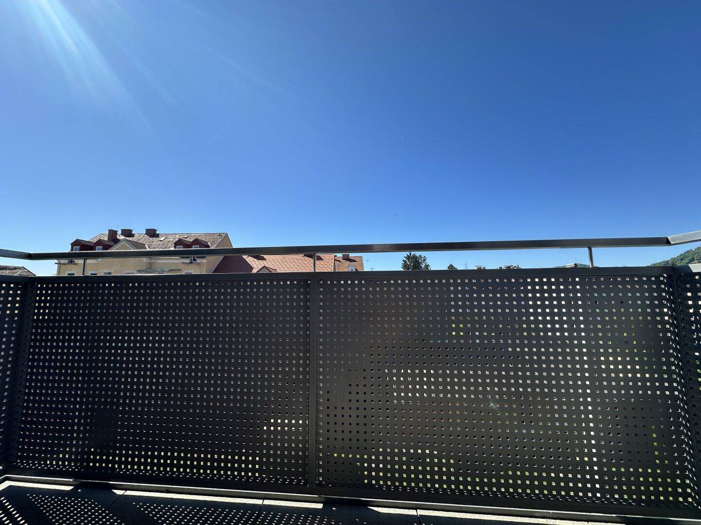Sonniger Balkon mit modernem Geländer und weitem Blick über die Umgebung.