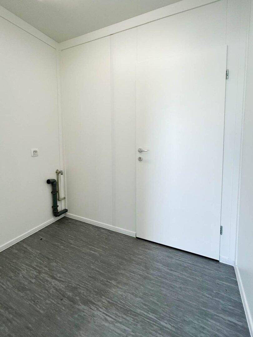 Kleiner, heller Raum mit Vinylboden und weiß gestrichenen Wänden, ideal als Abstellraum oder kleines Büro.