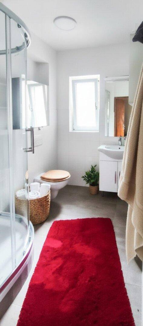 Modernes Badezimmer mit Duschkabine, WC und Waschbecken, hell gefliest.