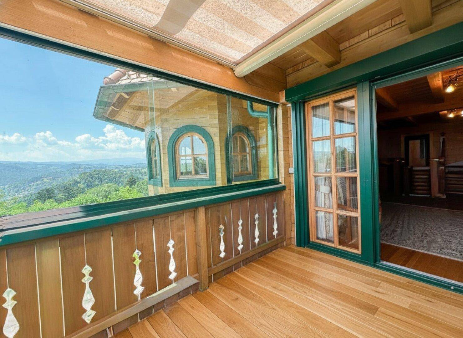 Verglaster Balkon mit atemberaubendem Panoramablick über grüne Hügel und Täler.