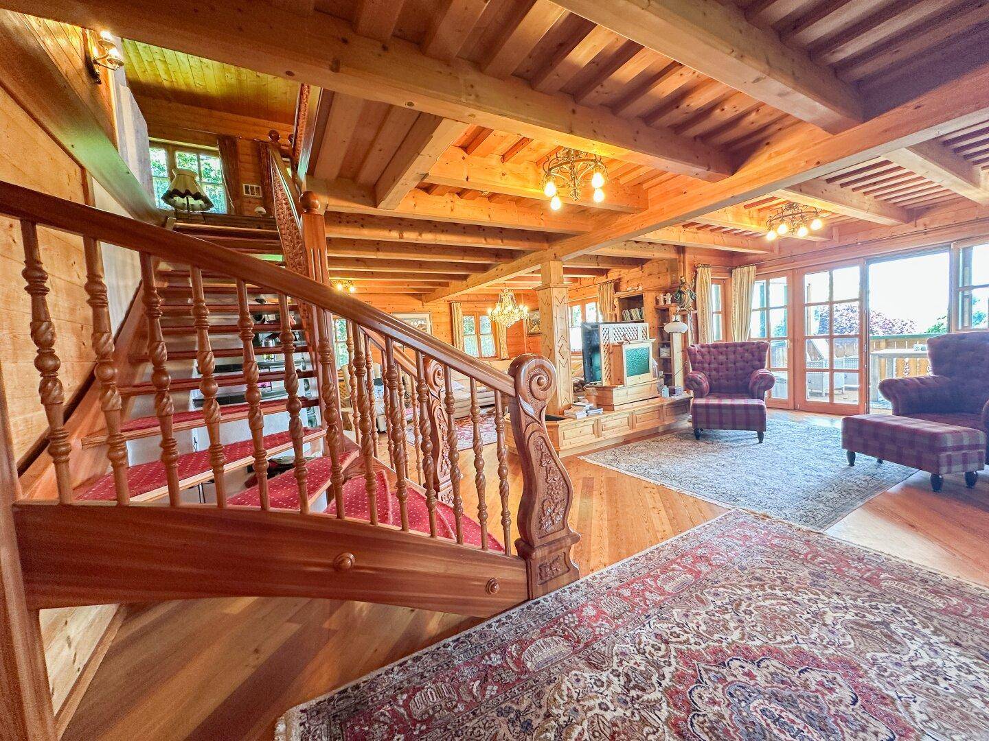 Elegante Holztreppe führt in den oberen Bereich, mit Blick auf das rustikale Wohnzimmer.