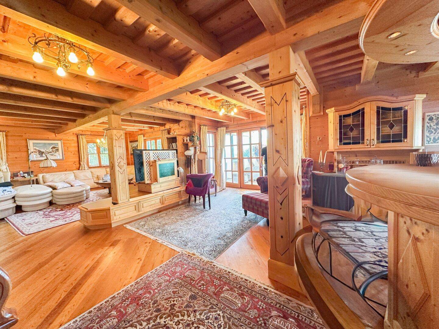 Geräumiges Wohnzimmer mit viel Holz, sichtbaren Deckenbalken und traditionellen Möbeln.