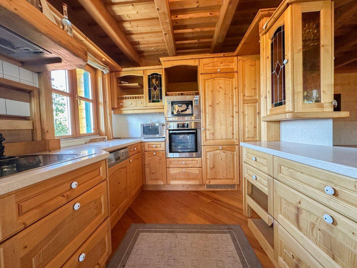 Gemütliche Holzküche mit integrierten Geräten und viel Stauraum, ideal für traditionelles Kochen.